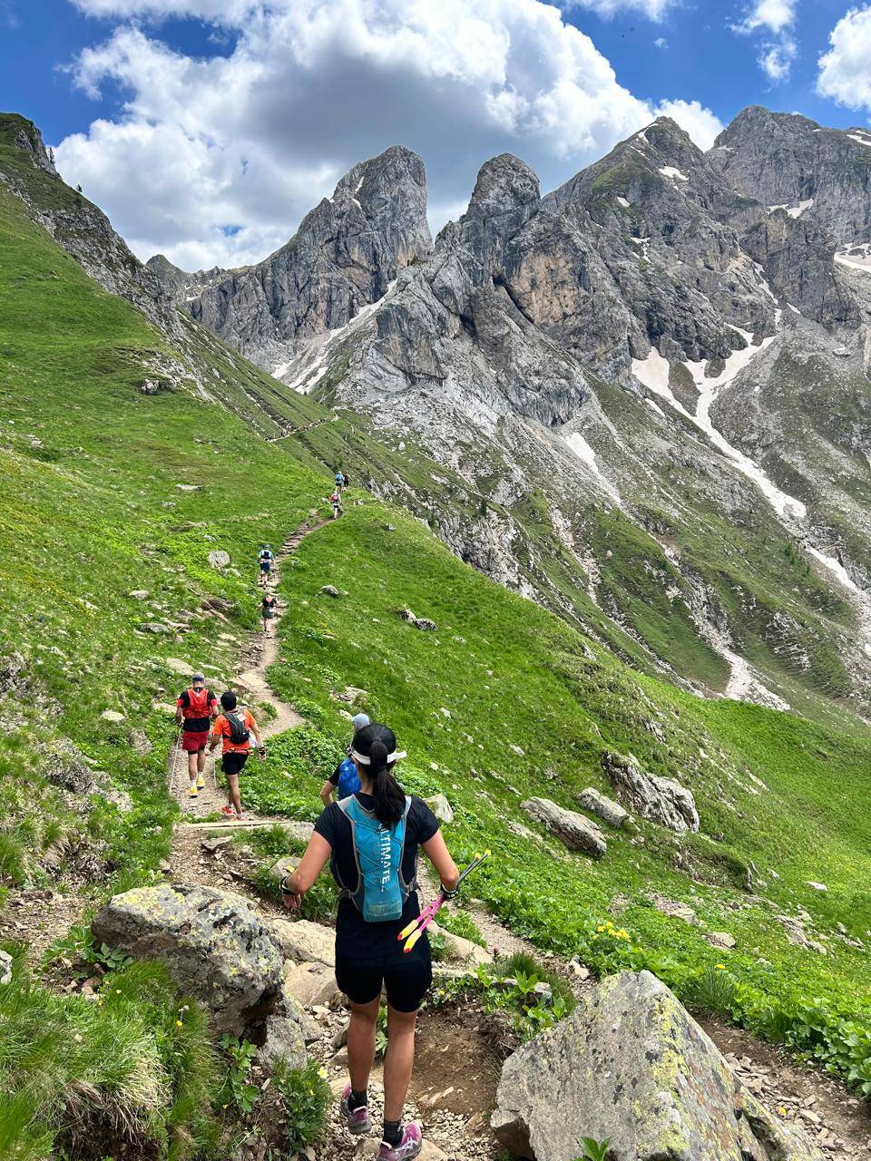 Fila de corredores numa trilha estreita na encosta da montanha
